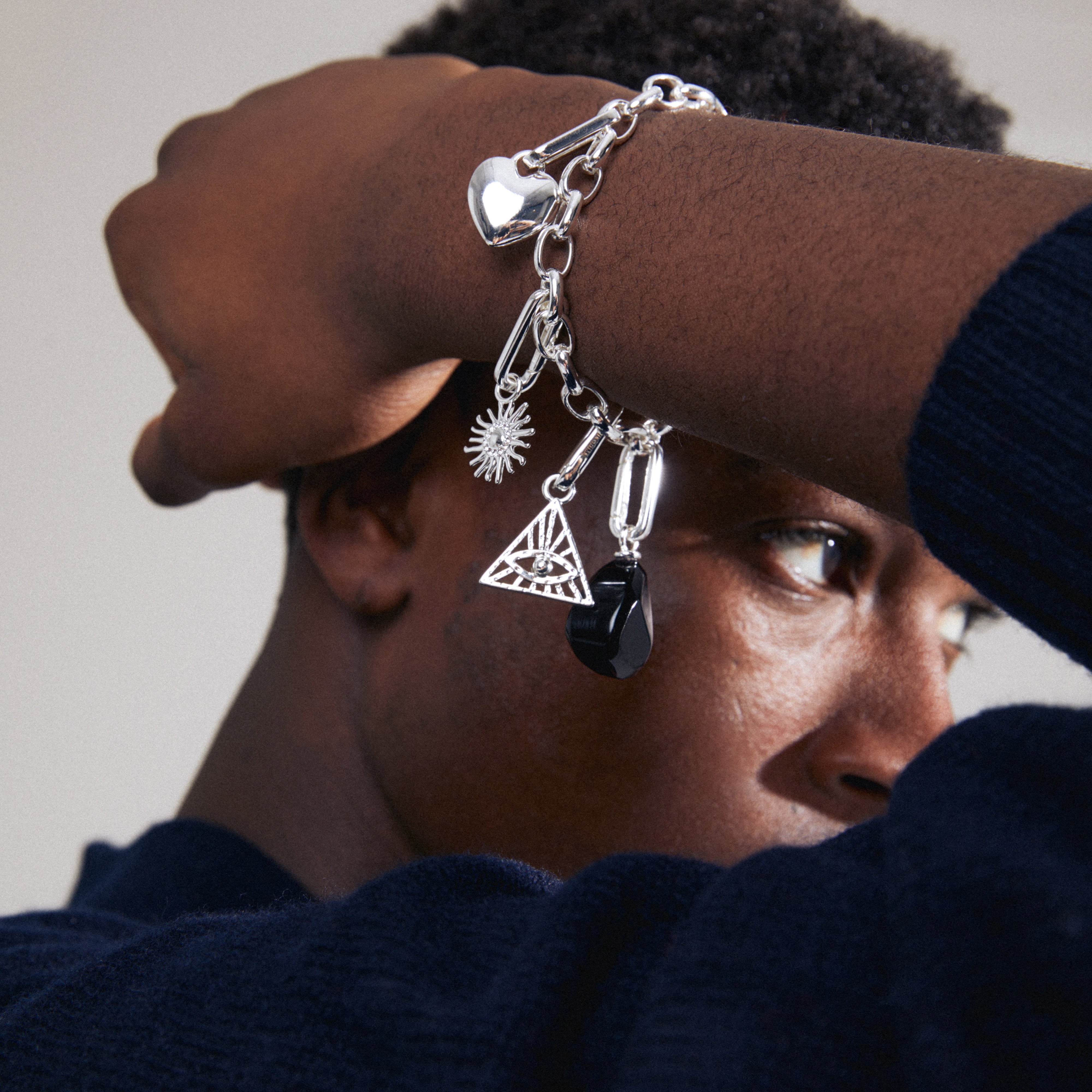 Close-up of a person's arm wearing Pilgrim's CHARM sun pendant, silver-plated, adorned with Preciosa crystals, attached to a chunky silver chain.