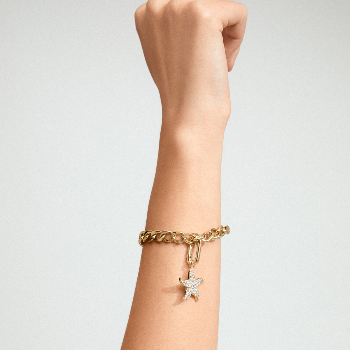 Gold-plated starfish pendant on a wrist, featuring Preciosa crystals, highlighting Pilgrim's unique and eco-conscious design. Perfect for personalizing your style with seaside elegance.