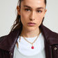 Woman wearing CHARM clover pendant gold-plated with a red enamel finish, styled with a leather jacket, showcasing a playful and trendy fashion accessory.