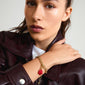 Woman wearing a leather jacket showcasing the CHARM clover pendant gold-plated by Pilgrim, featuring a red enamel finish and crafted from recycled materials.