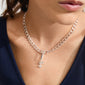 Woman wearing the CHARM symbols pendant, silver-plated with cross, anchor, and heart, showcasing its intricate design in a close-up view.