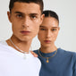 Two young adults showcase Pilgrim's CHARM peace dove pendant, gold-plated. The coin pendant complements their casual T-shirts, exuding a calm, harmonious style.