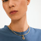 Person wearing a simple blue top with Pilgrim's CHARM rough heart pendant, a unique gold-plated choker-style necklace featuring a rustic heart-shaped padlock.