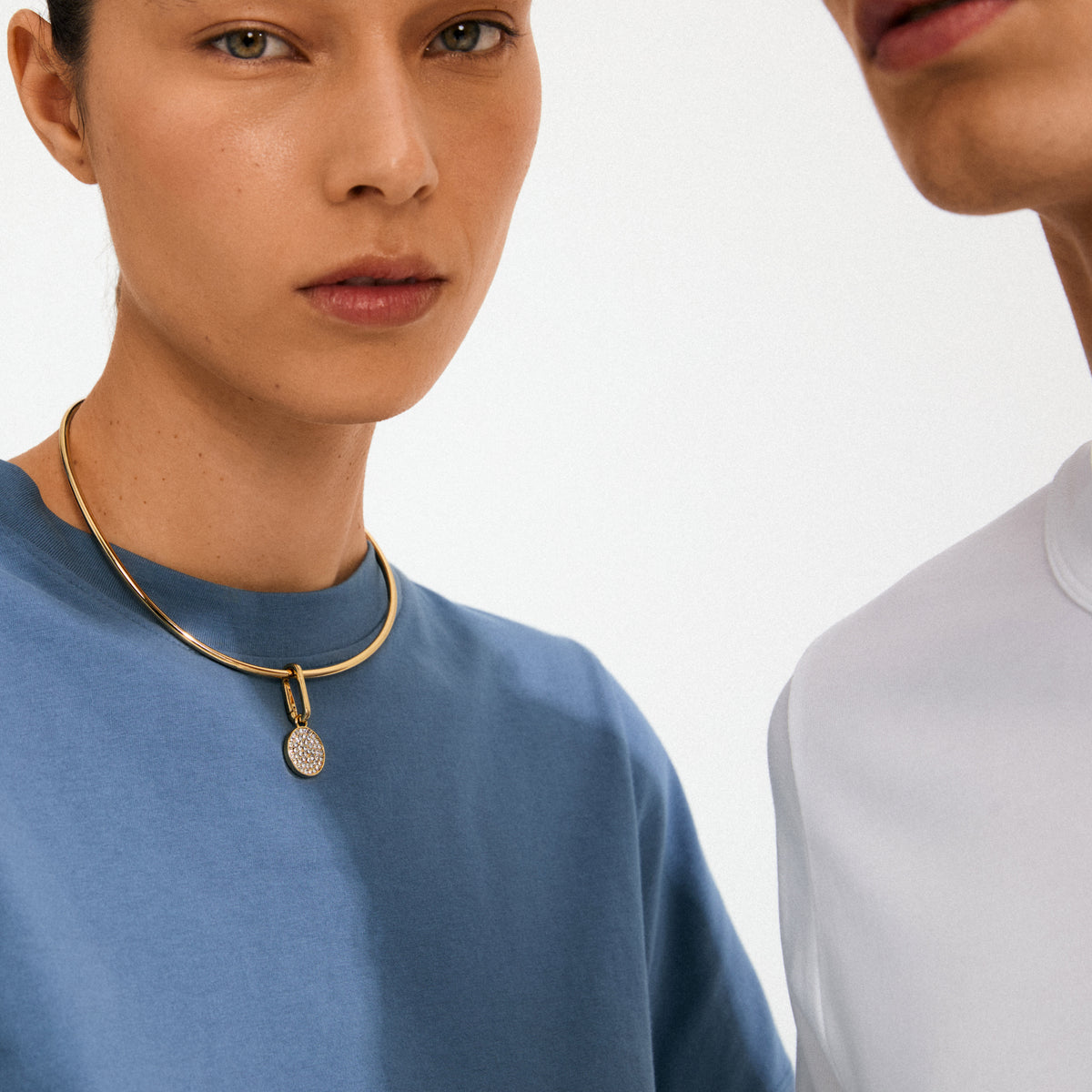 Woman wearing CHARM crystal coin pendant, gold-plated, with pavé-set crystals on a polished choker, showcasing Pilgrim's blend of timeless style and modern elegance.