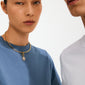 Woman wearing CHARM crystal coin pendant, gold-plated, with pavé-set crystals on a polished choker, showcasing Pilgrim's blend of timeless style and modern elegance.