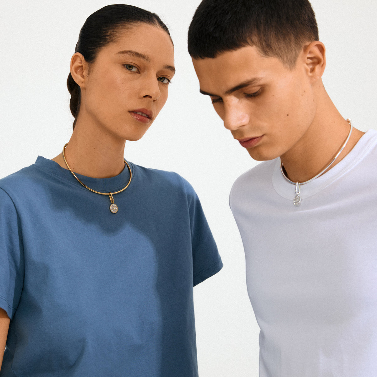 Models showcasing Pilgrim's CHARM crystal coin pendant, gold-plated, on torc necklaces. The pendant, adorned with Preciosa crystals, offers a personalized, eco-friendly touch.