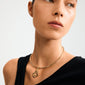 Woman wearing Pilgrim's CHARM curl pendant, a gold-plated abstract loop on a sleek choker, highlighting creative style and craftsmanship with a Scandinavian touch.