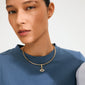Close-up of the CHARM eye pendant, a gold-plated necklace with Preciosa crystals, elegantly styled on a woman in a blue top, highlighting its intricate design.