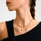 Woman wearing Pilgrim's CHARM bright gold-plated pendant with sun-shaped design and Tiger Eye stone, paired with a black asymmetrical top.