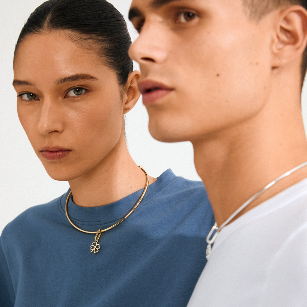 Model duo showcasing Pilgrim's CHARM clover pendant, silver-plated, on choker necklaces, embodying Scandinavian quality and personal style in a minimalist, trendy design.