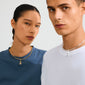 Two people wearing crew-neck tees and rigid hoop necklaces. The man features Pilgrim's silver-plated CHARM f... pendant, adding an edgy, customizable touch.