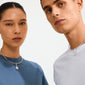 Models wearing Pilgrim's CHARM crystal coin pendant; a silver-plated necklace with sparkling crystals, highlighting personal style and sustainable fashion.