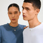Two young adults wearing Pilgrim's silver-plated eye pendant necklaces, each featuring intricate designs with Preciosa crystals, styled in a minimalist, editorial shot.