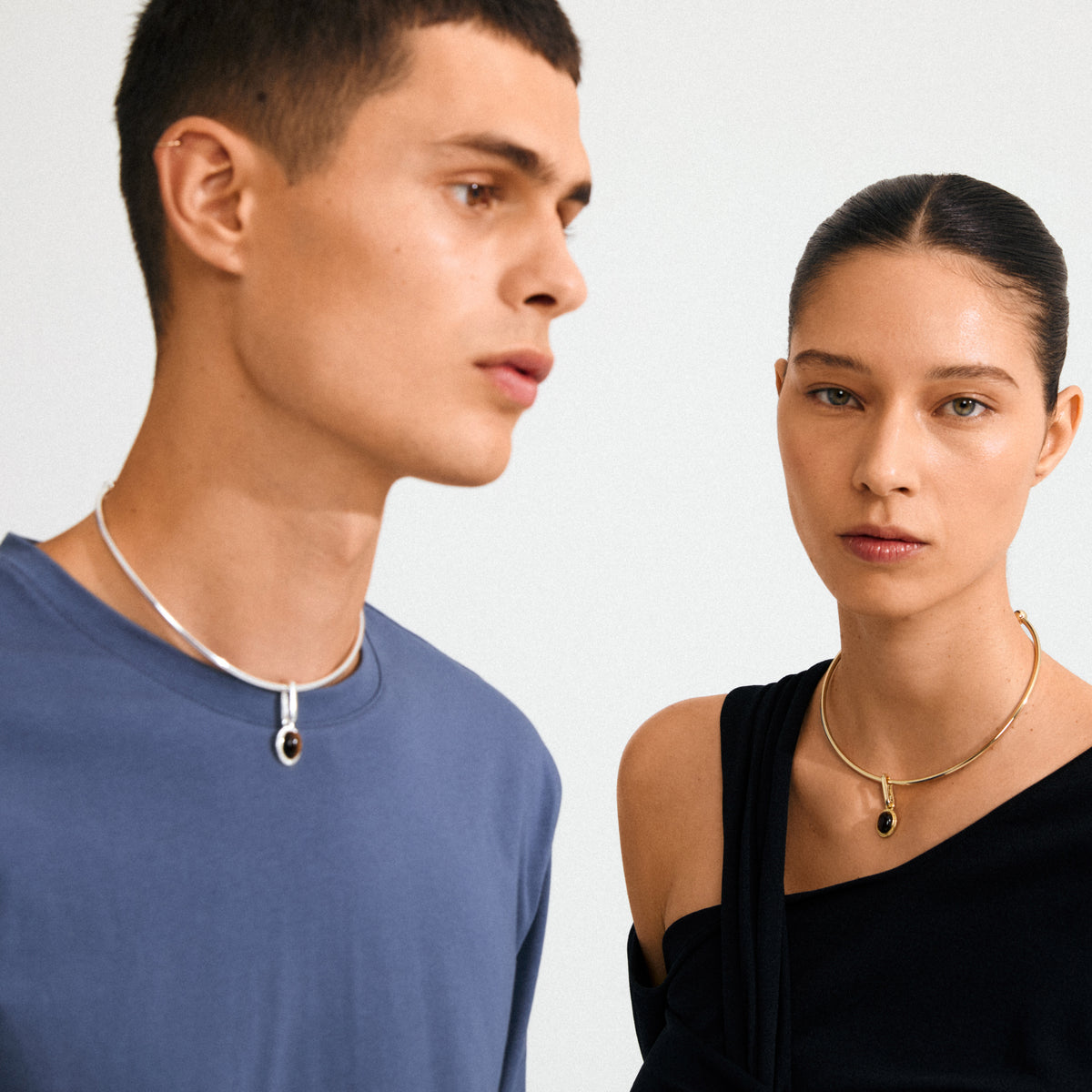Models showcase Pilgrim's CHARM medallion pendant, silver-plated, with Tiger Eye stone, reflecting minimalist, modern Scandinavian style.