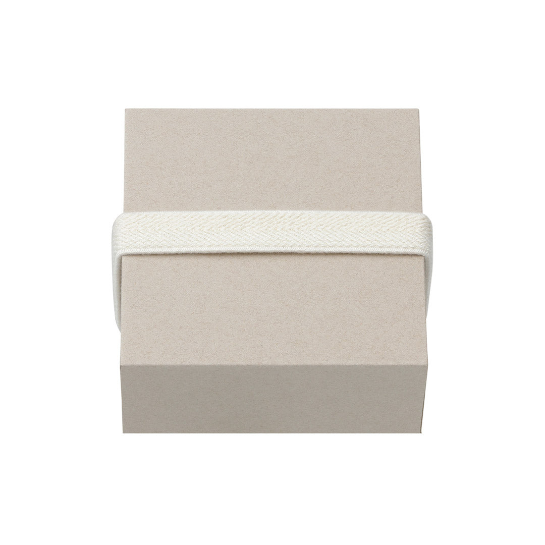 Medium gift box, W85 x H85 x D41 mm, featuring a cream fabric strap wrapped around its plain beige surface, ideal for stylish, minimalist presentations.
