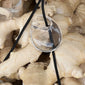 FREJA WEWER x PILGRIM Aqua necklace: Teardrop glass pendant on black cord atop fresh ginger rhizomes, showcasing bold simplicity and sustainable style.