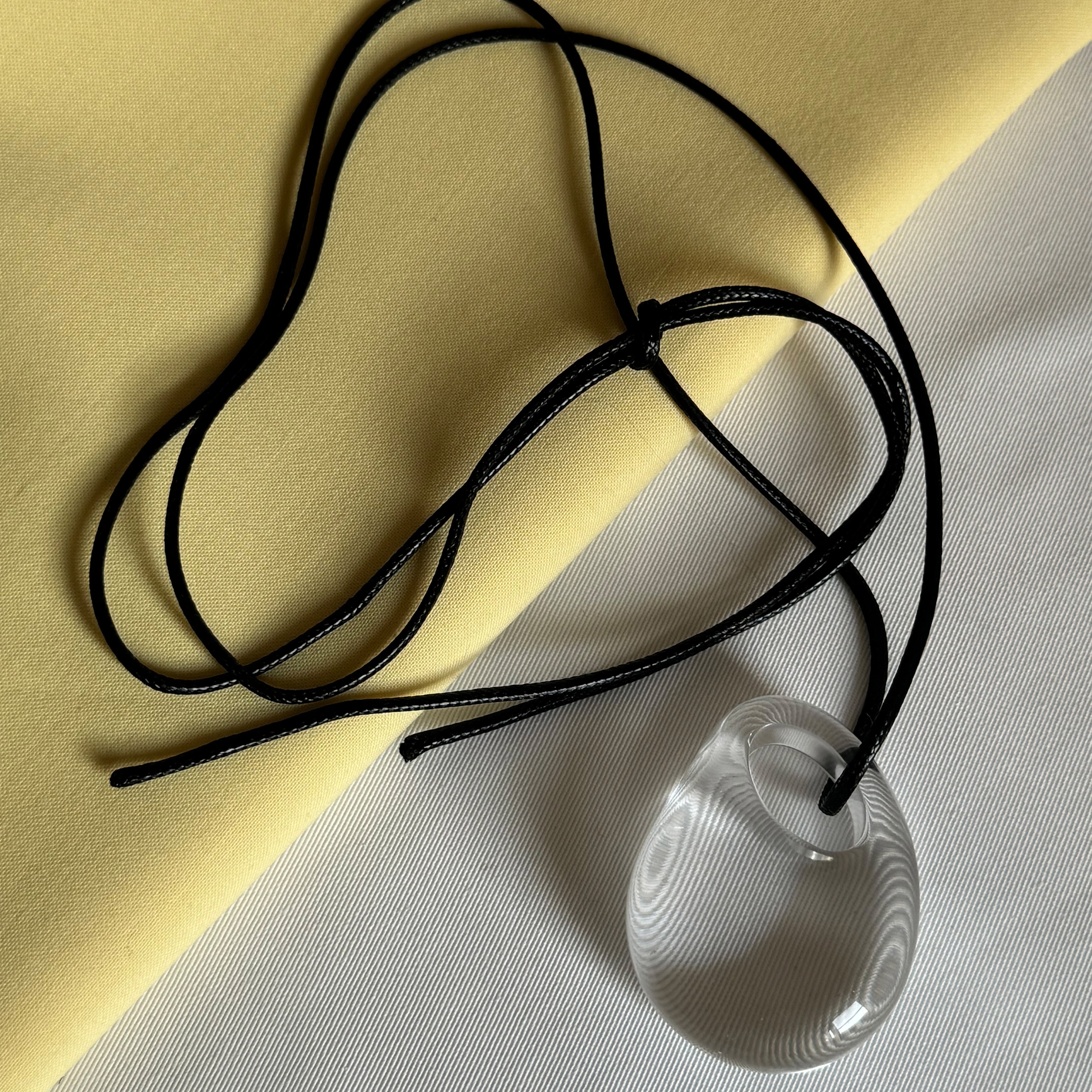 FREJA WEWER x PILGRIM Aqua necklace featuring a clear teardrop pendant on a sleek, adjustable black cord, crafted from recycled acrylic for eco-friendly style.