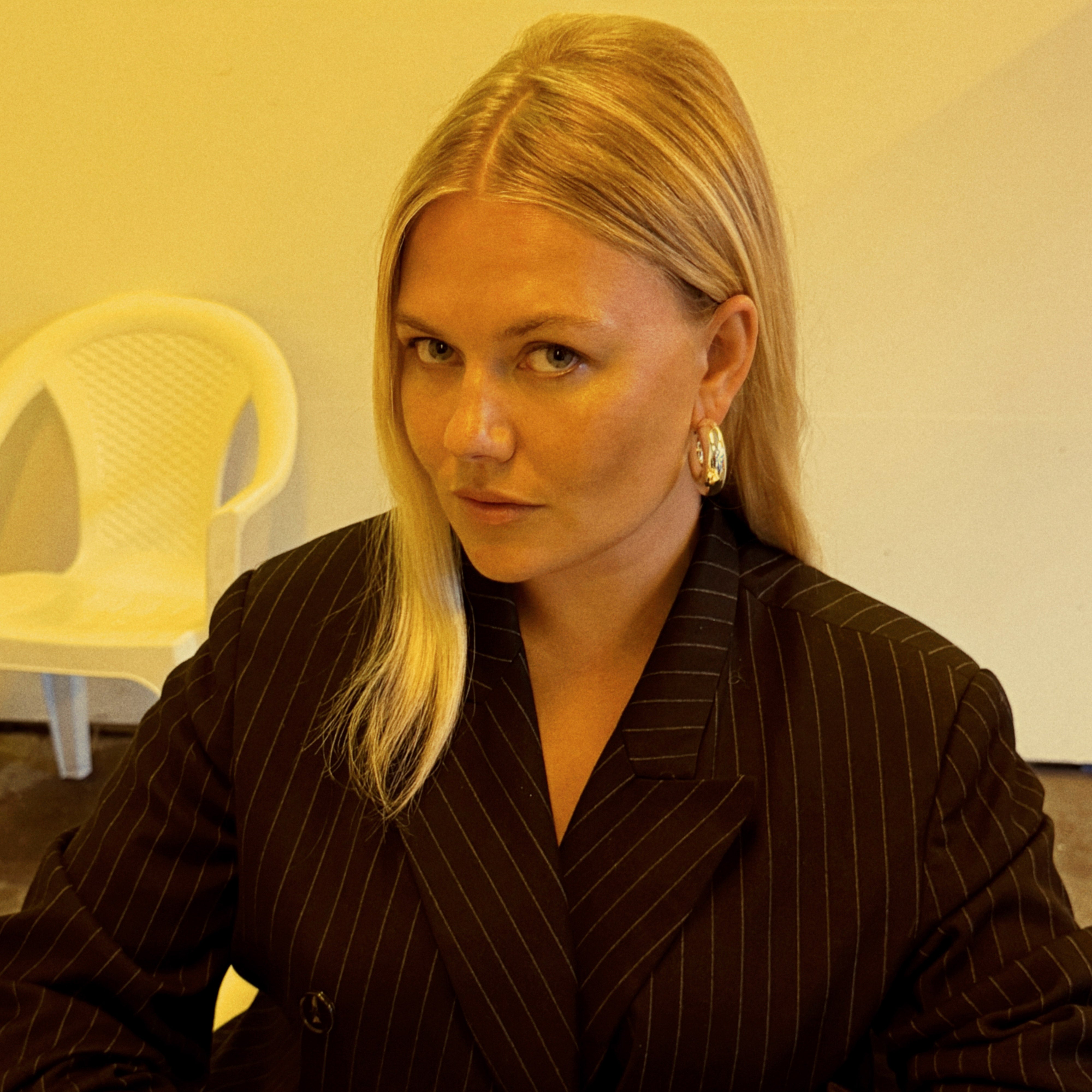 A woman in a black suit wearing FREJA WEWER x PILGRIM Firenze medium silver-plated hoops, showcasing bold, chunky statement earrings perfect for elevating outfits.