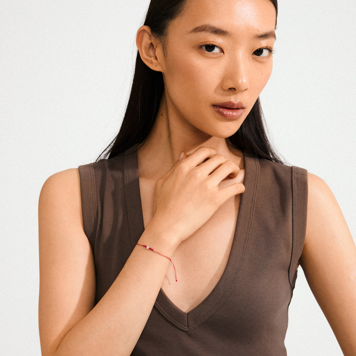 OCTOBER birthstone bracelet: Red string with an opal, adjustable knot closure, worn on a woman's wrist, complementing her boho style. Ideal for creativity and inspiration.