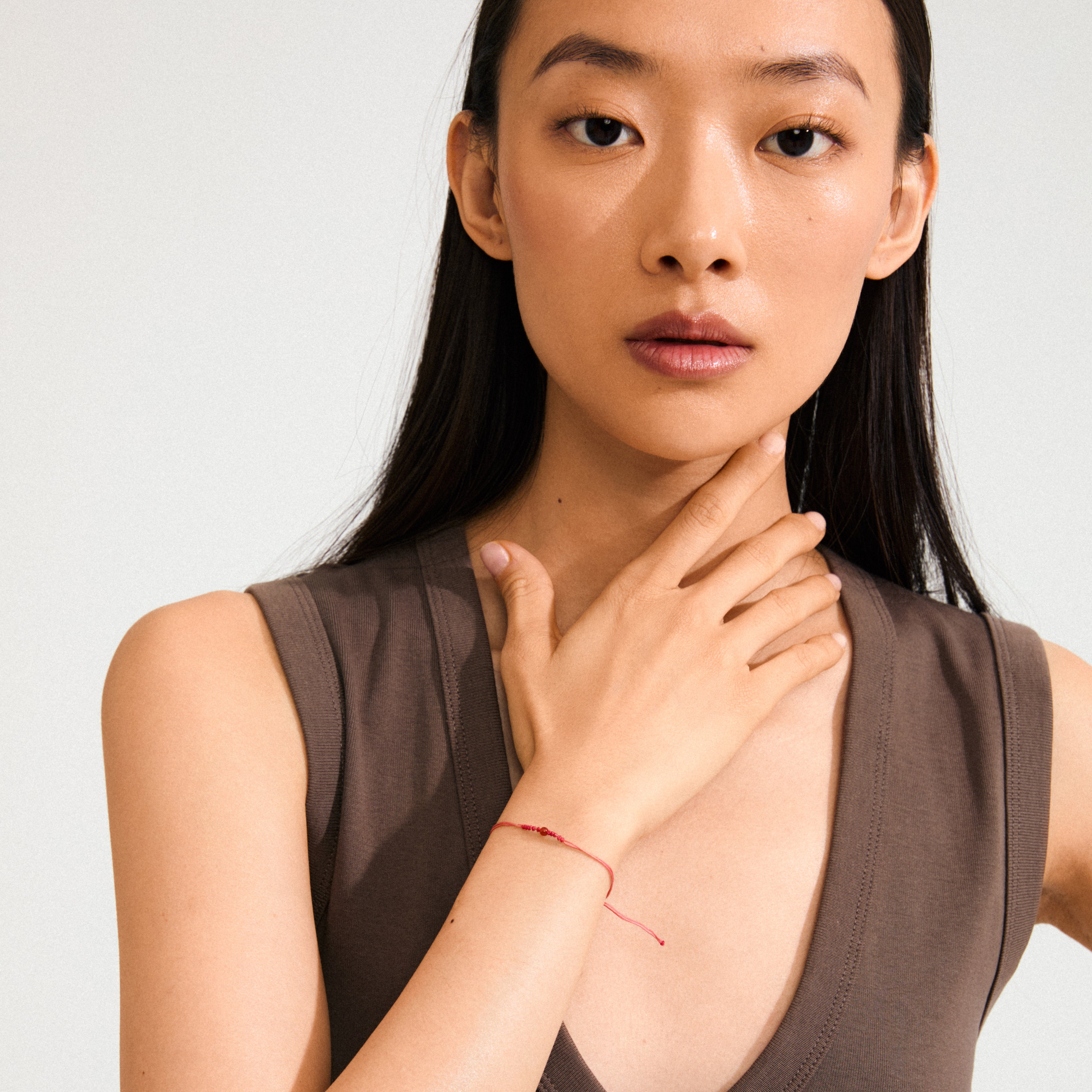 Woman wearing JULY birthstone bracelet, featuring a red cotton cord and Red Agate stone, symbolizing courage and determination.