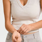 Woman wearing a white shirt adjusts JULY birthstone bracelet, featuring red cotton cord and Red Agate, on her wrist. Perfect minimalist accessory from Pilgrim.