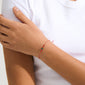 A person wearing the MAY birthstone bracelet with a red cord and Green Agate, showcasing its delicate charm and earthy, harmonious style.