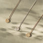 LIBRA Zodiac Sign Coin Necklace, silver-plated, with a double-sided pendant featuring a zodiac motif and crystal constellation, displayed on a concrete surface.