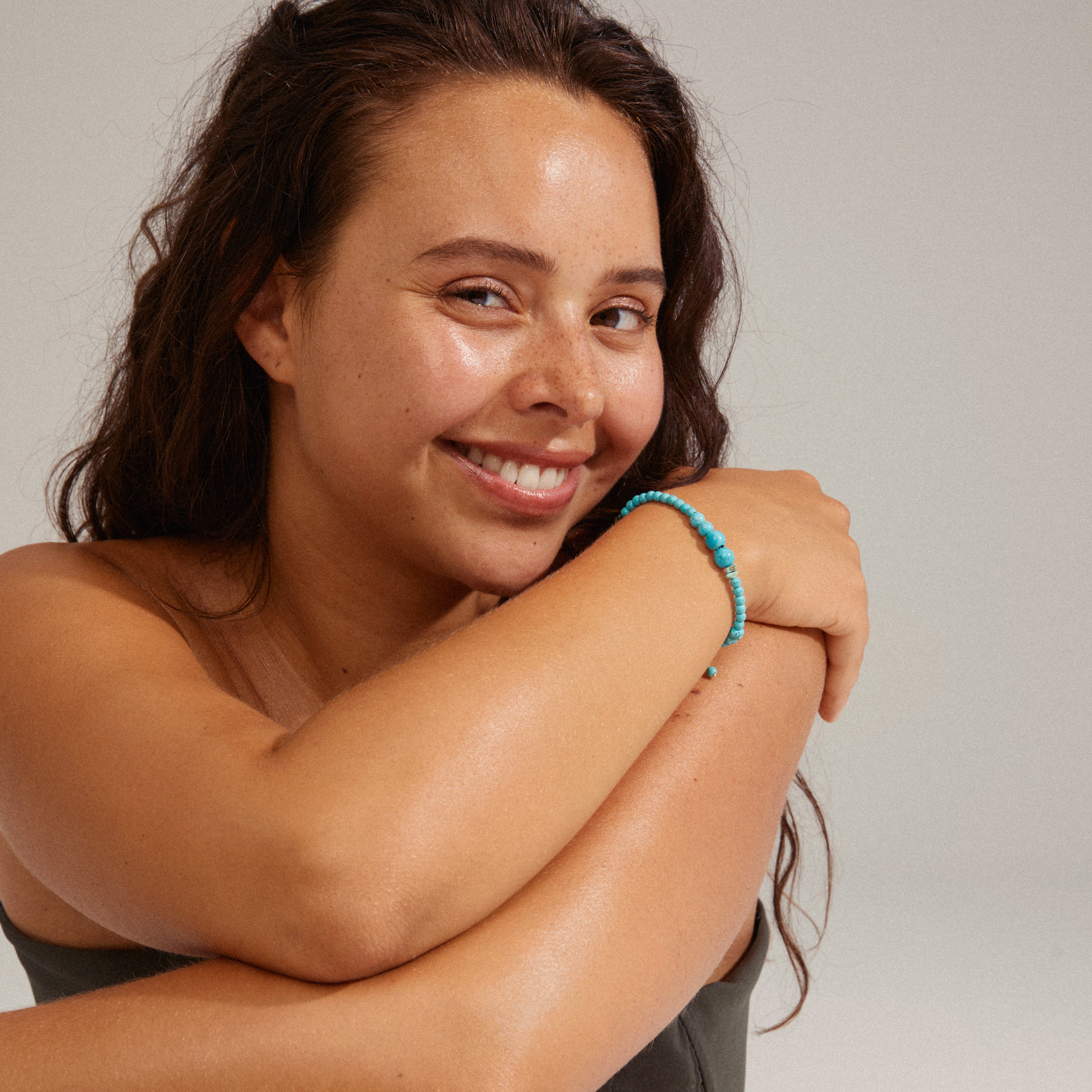 Woman wearing SOULMATES bracelet blue/gold-plated with turquoise and malachite beads, showcasing its asymmetrical style and unique color variations.