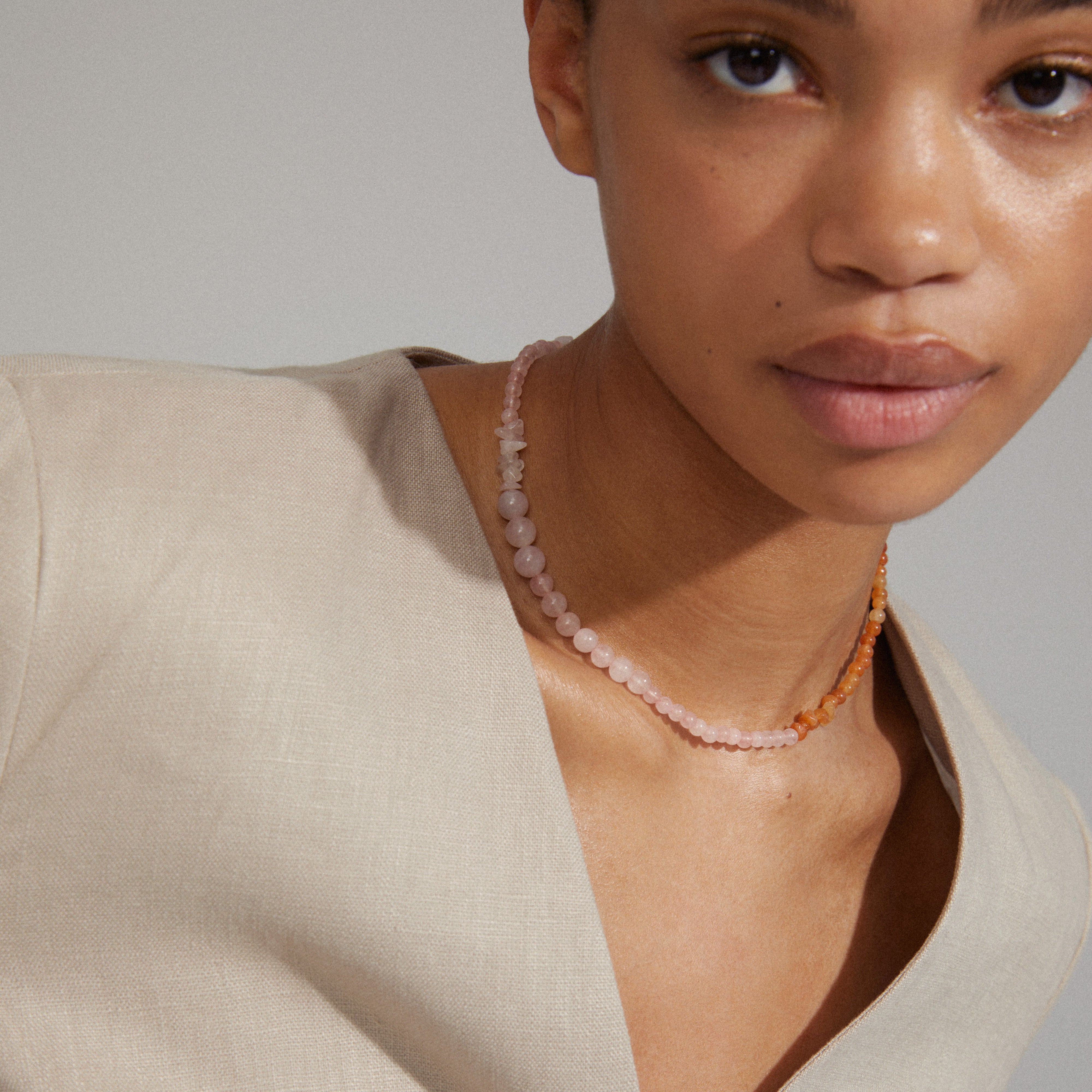 Close-up of a woman wearing the SOULMATES necklace rose/gold-plated, featuring genuine rose quartz and red aventurine stones representing love and strength.