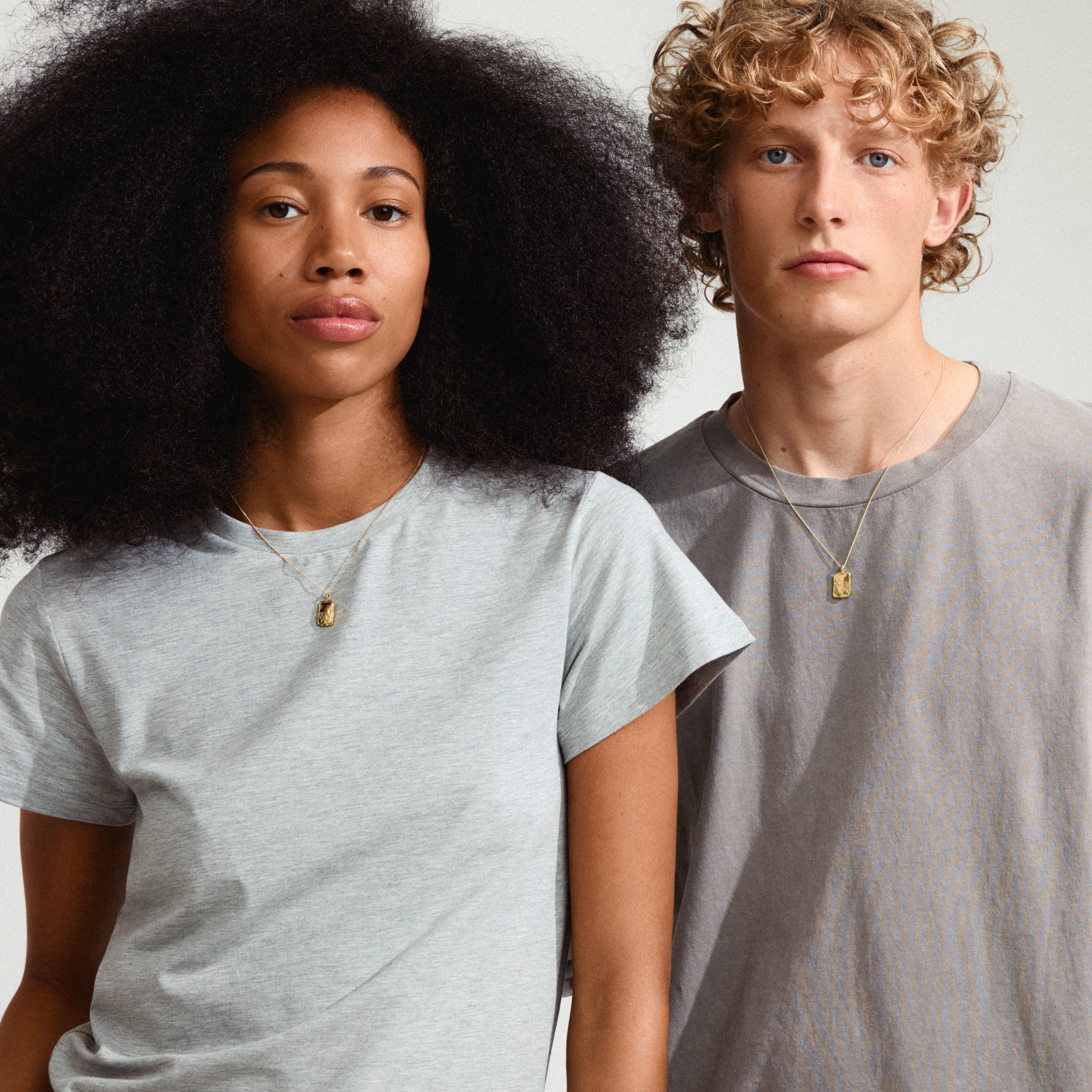 TAURUS Zodiac Sign necklace, gold-plated, featuring a reversible square coin pendant with a rustic look, worn by a man and woman.