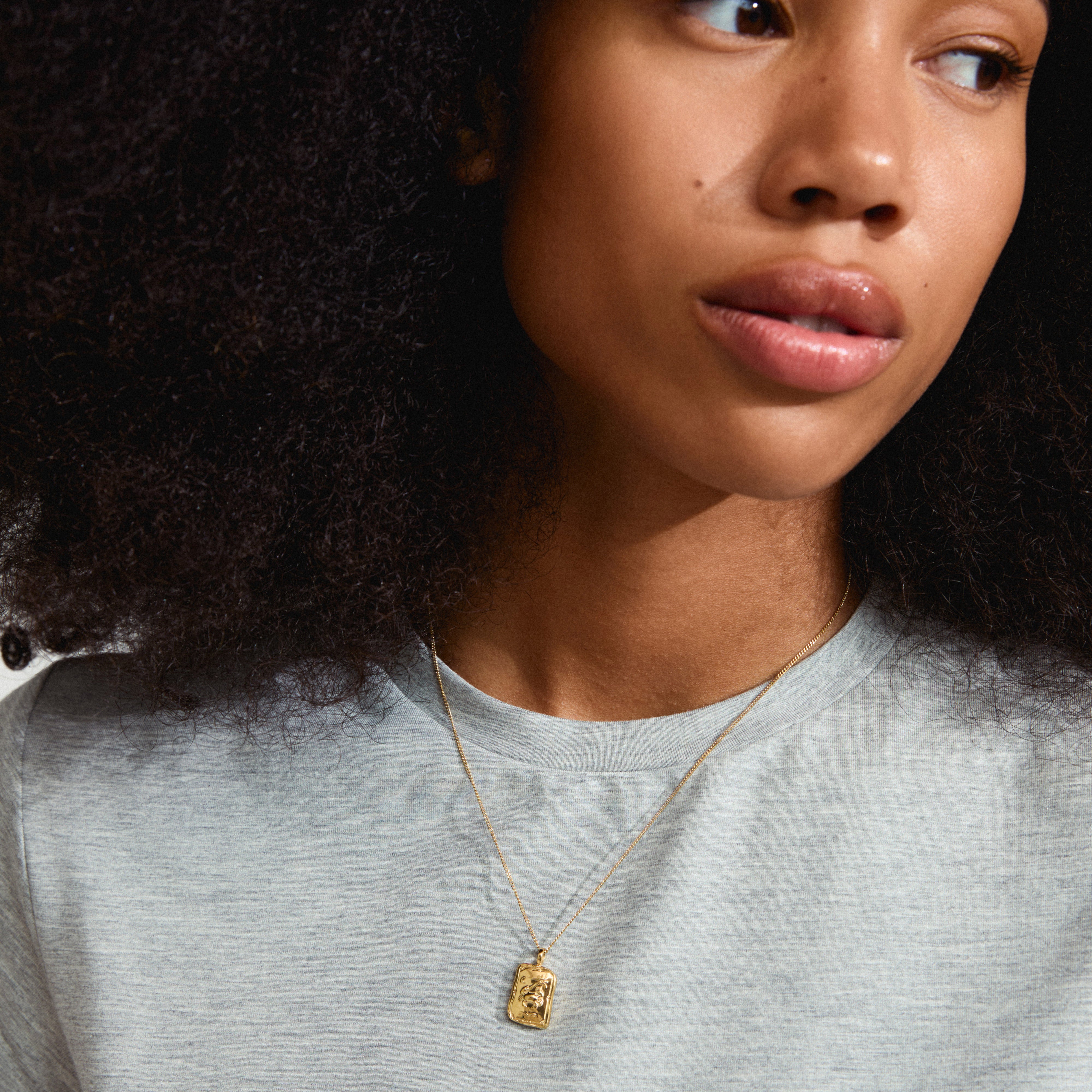 Gold-plated CANCER Zodiac Sign necklace with square coin pendant, displaying a crab motif, worn by a woman. Necklace features a dual design with sparkling crystals.