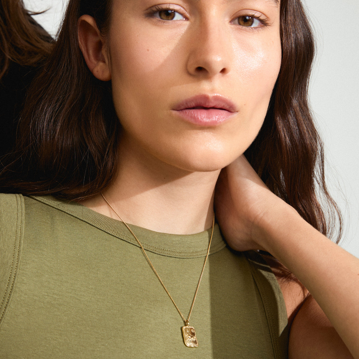 Woman wearing Pilgrim's LEO Zodiac Sign necklace, featuring a gold-plated chain with a reversible square coin pendant in a Leo motif and constellation design.