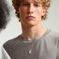 Curly-haired person wearing Pilgrim's TAURUS Zodiac Sign necklace, featuring a silver-plated chain with a square coin pendant showcasing a Taurus motif and crystal constellation.