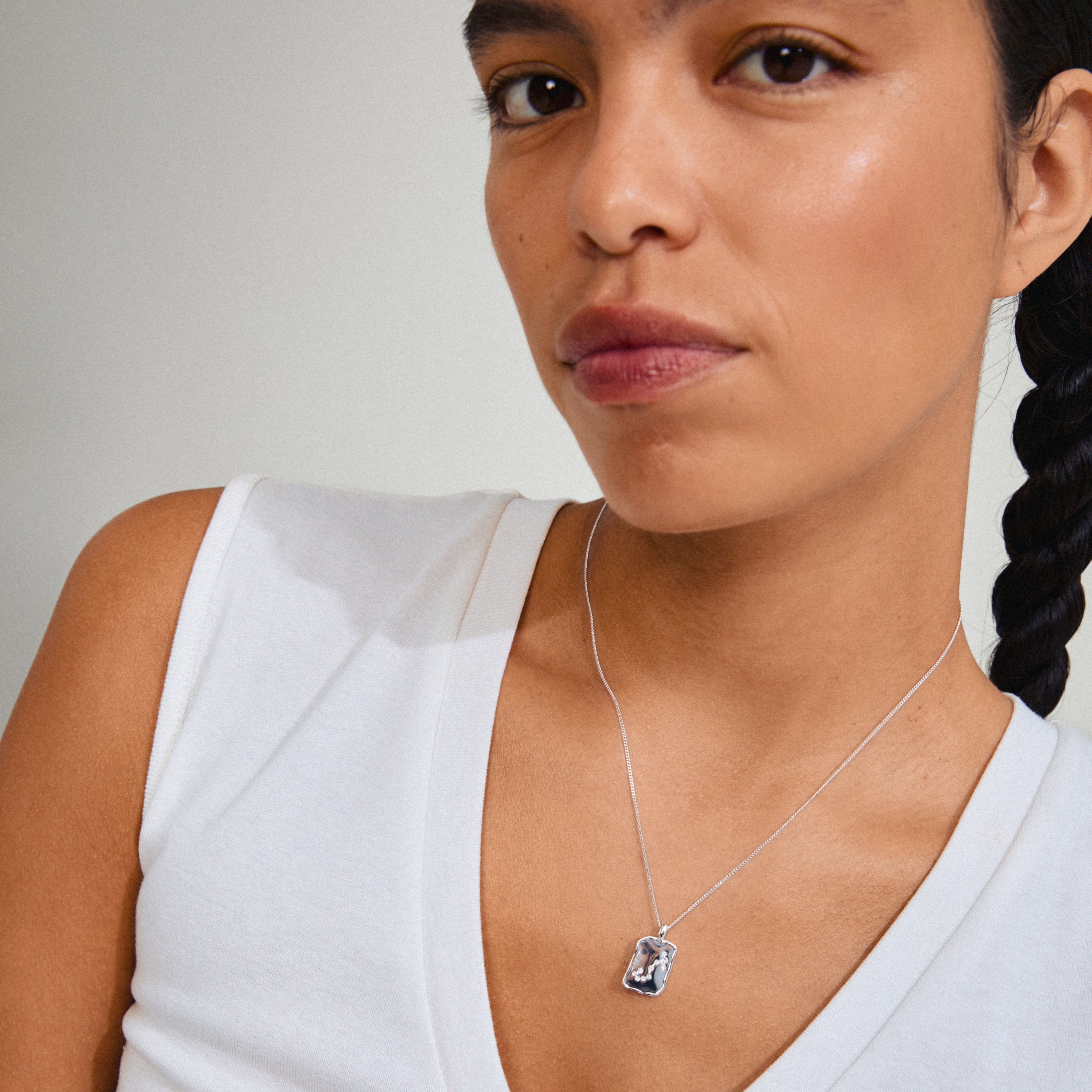 SCORPIO Zodiac Sign necklace, silver-plated, featuring a square coin pendant with Scorpio motif and sparkling constellation design, worn by a woman.