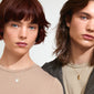 CAPRICORNUS Zodiac Sign necklace, silver-plated, featuring a dual-design pendant with Capricorn motif and sparkling constellation, worn by a woman with short red hair.