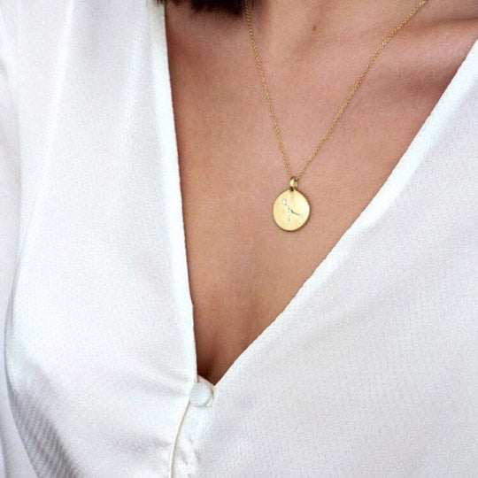 Gold-plated GEMINI Zodiac Sign Coin Necklace featuring a round pendant with crystal stones, worn by a woman. Perfect for style-conscious, personal expression.