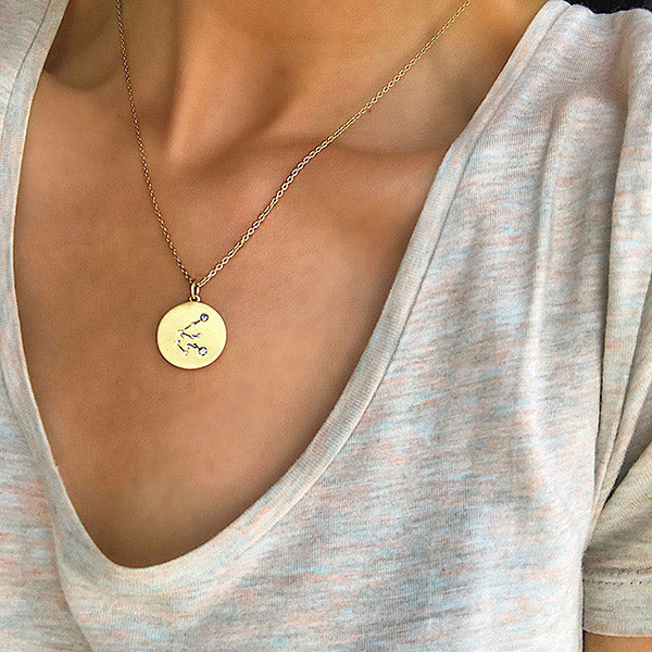 SCORPIO Zodiac Sign Coin Necklace, gold-plated, featuring a round pendant with crystal stones forming the Scorpio symbol, worn by a person.