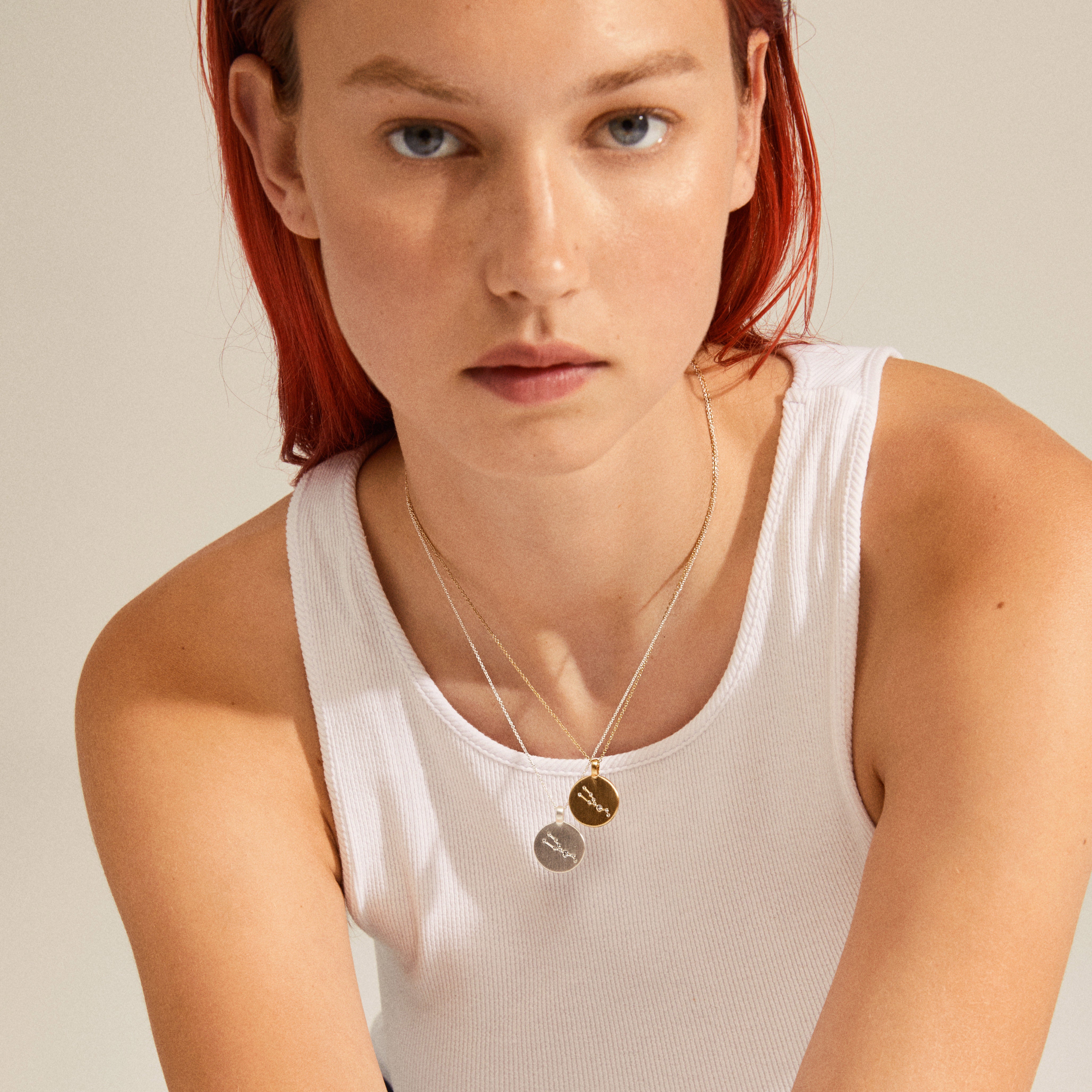 SCORPIO Zodiac Sign Coin Necklace, gold-plated, featuring a round pendant with crystal stones, worn by a woman with red hair and a white tank top.