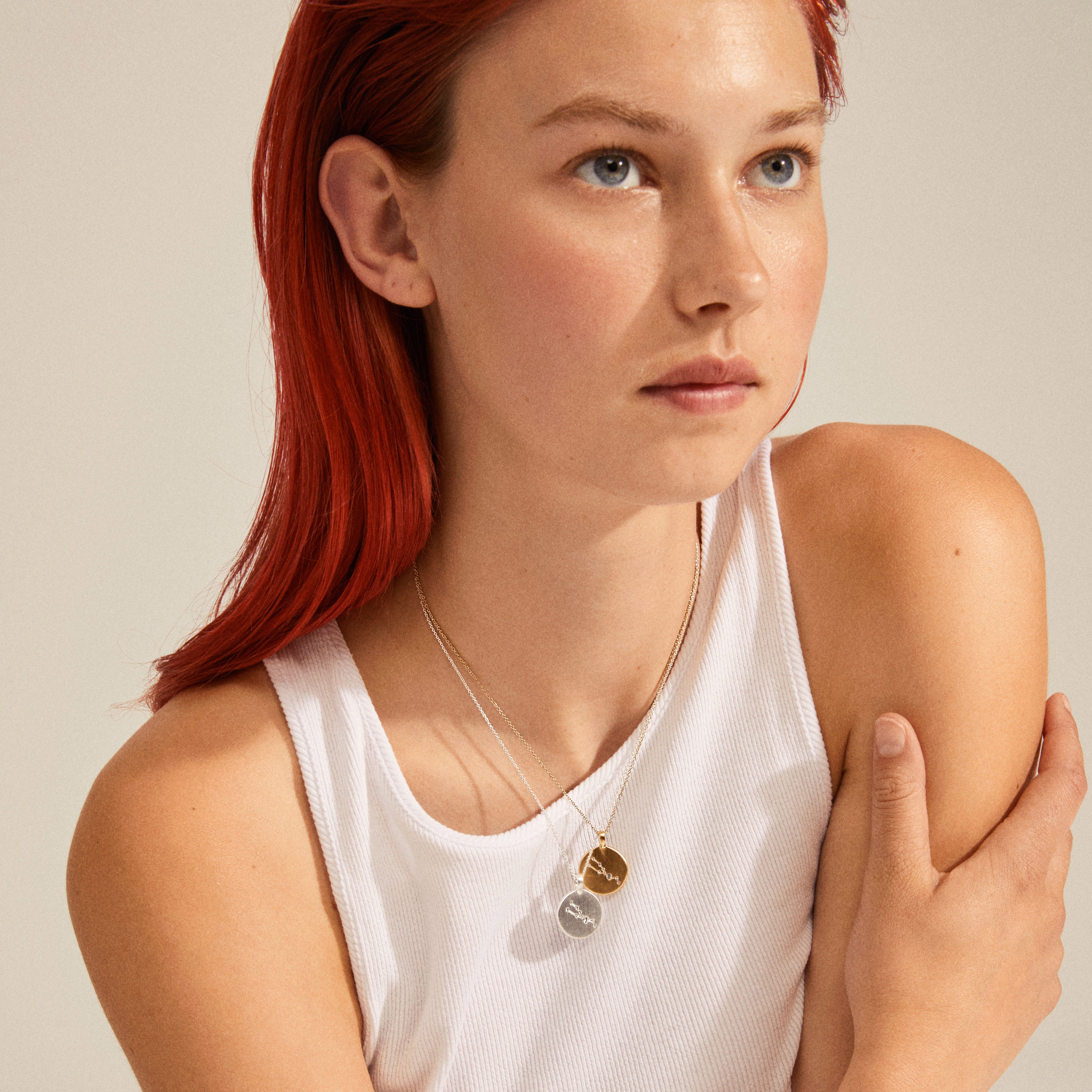 SAGITTARIUS Zodiac Sign Coin Necklace, silver-plated, with a round pendant featuring crystal stones, worn by a woman with red hair and a white tank top.
