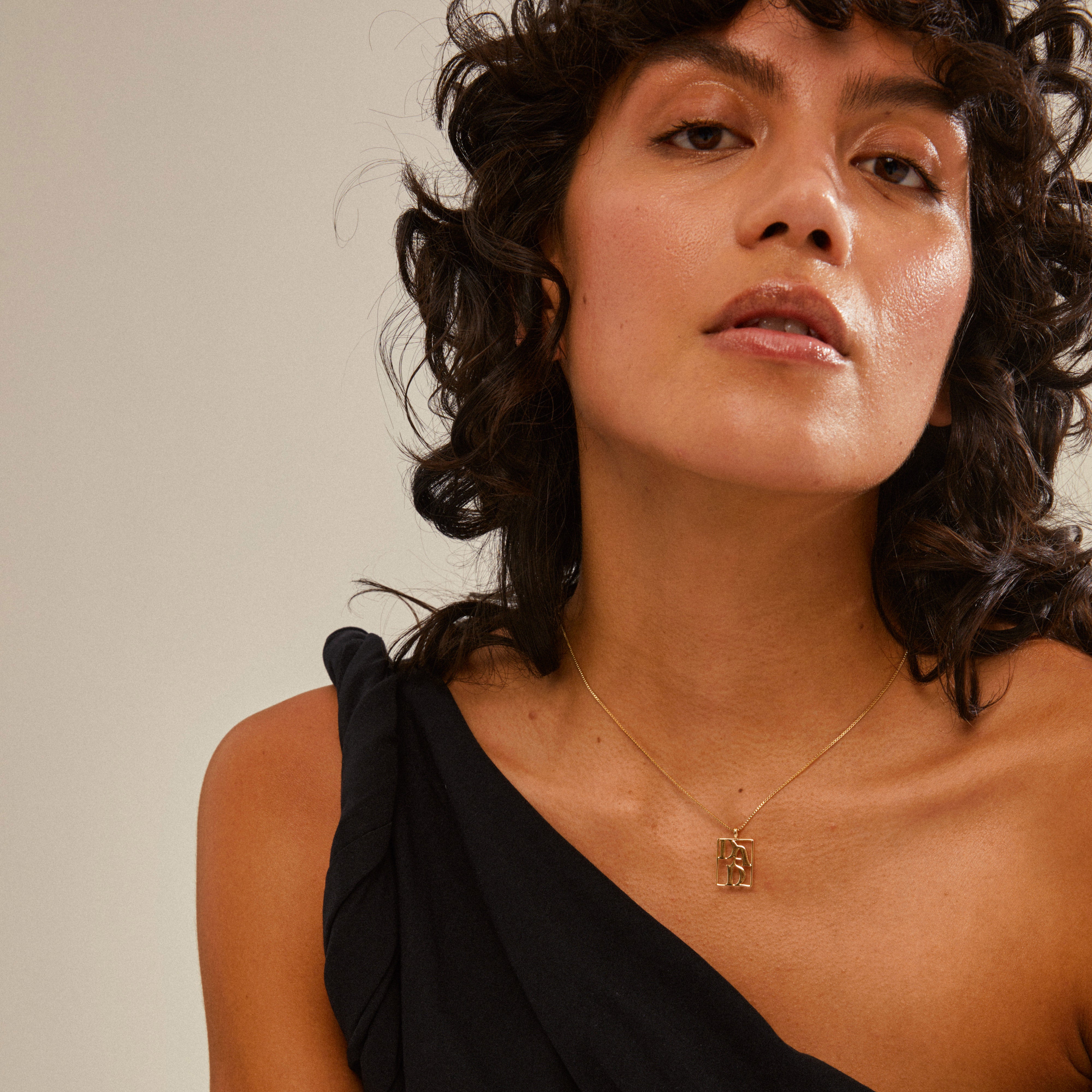 Woman wearing the LOVE TAG, DAD necklace, a gold-plated piece with a square pendant inscribed DAD, reflecting Pilgrim's blend of timeless and trendy design.