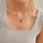 LOVE TAG, MOM necklace gold-plated, featuring a shiny rectangular pendant on a light grey tank top, exemplifying Pilgrim's blend of timeless and trendy Scandinavian design.