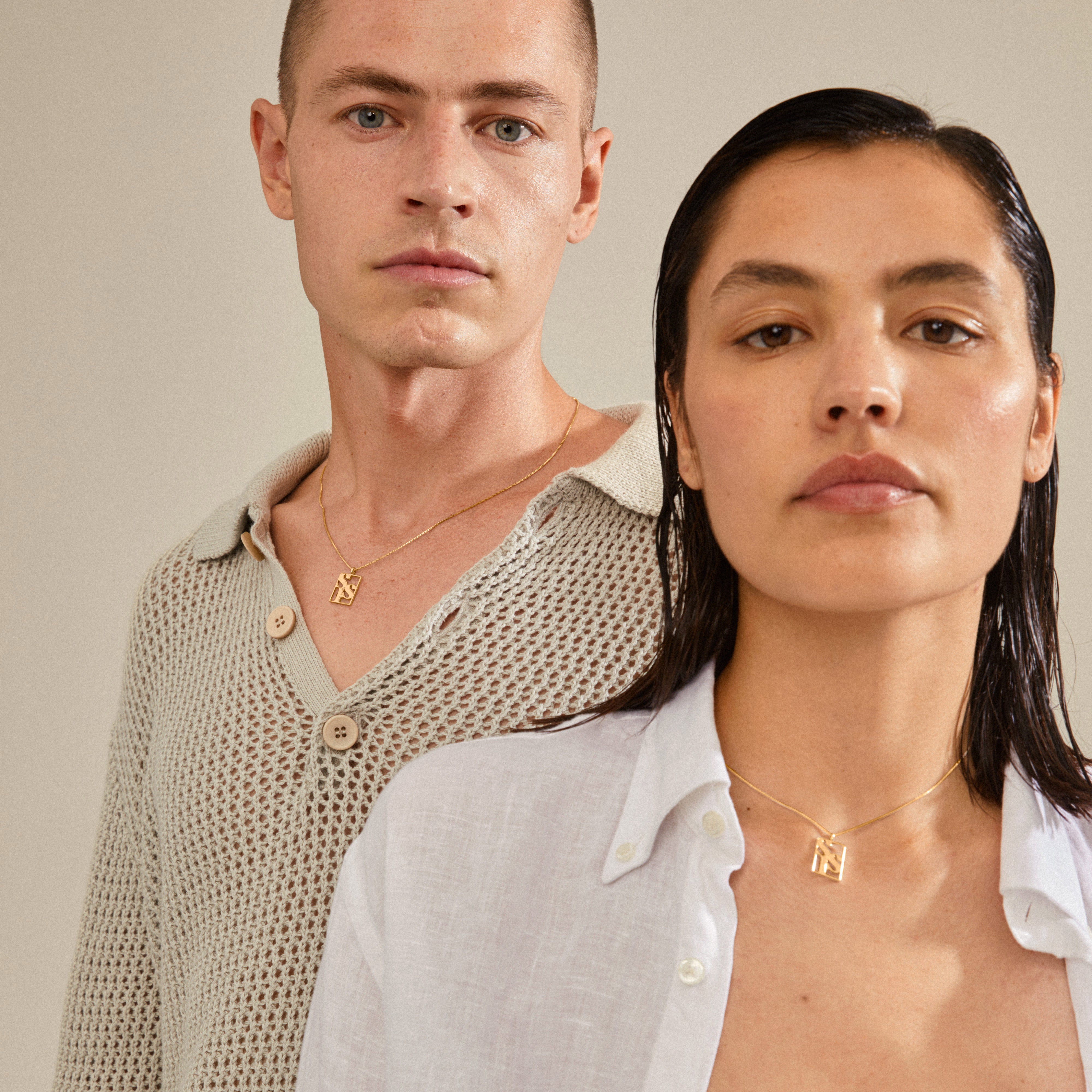 Man and woman showcasing Pilgrim's LOVE TAG, SIS gold-plated necklace with square pendant, ideal for layering. Features adjustable recycled chain for sustainable fashion.