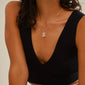Person wearing LOVE TAG, MOM necklace, featuring a silver-plated chain and square pendant with MOM, paired with a ribbed black sleeveless top.