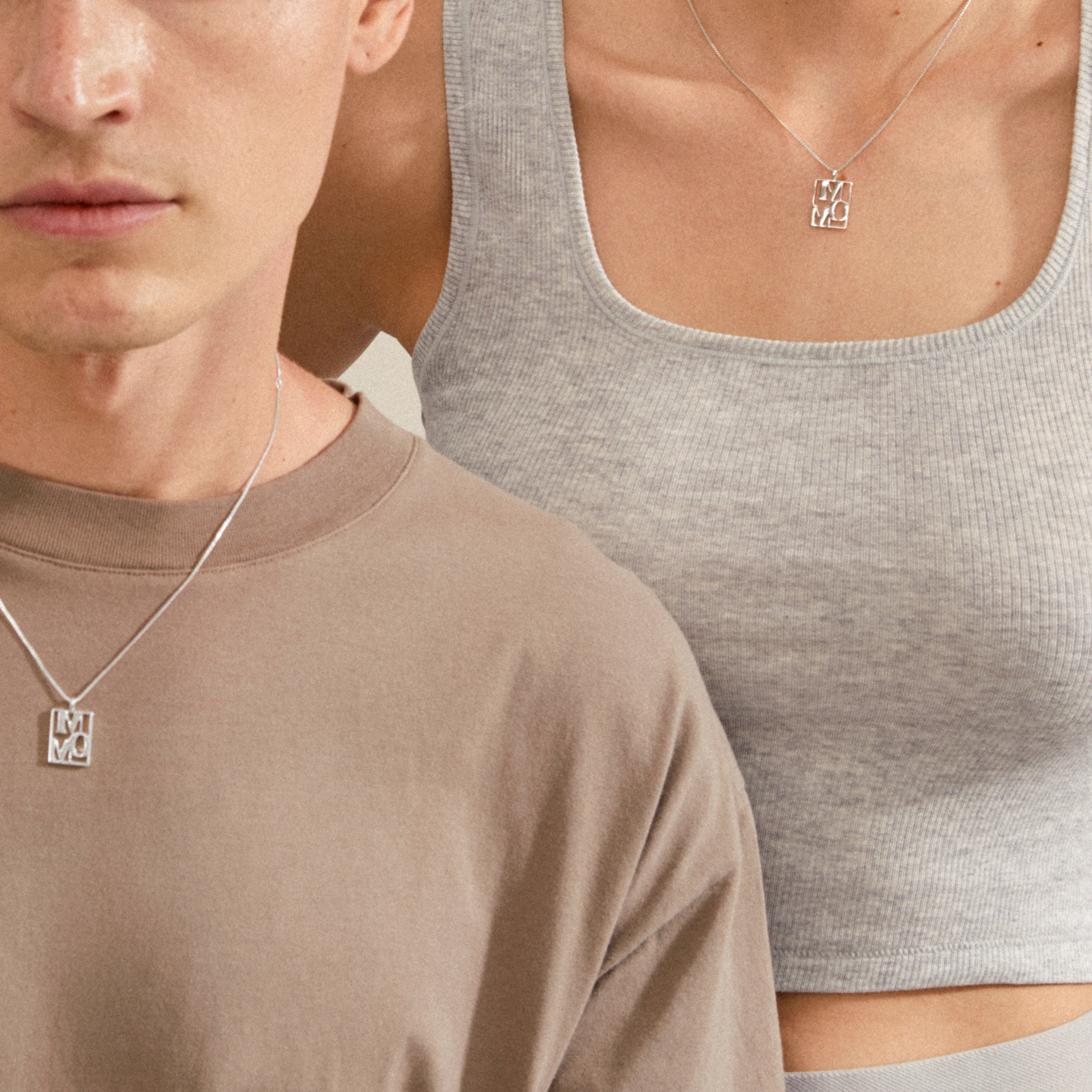 Two models showcase Pilgrim's silver-plated LOVE TAG, MOM necklace, featuring a geometric pendant on fine chains, embodying love and style.