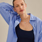 Woman showcasing a silver-plated LOVE TAG, BRO necklace from Pilgrim, featuring a square pendant inscribed with BRO on an adjustable chain.