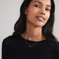 Woman wearing LUCK necklace, a gold-plated, cursive script pendant on a chain, embodying personal style and Scandinavian craftsmanship by Pilgrim.