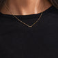 Gold-plated LUCK necklace with a cursive script pendant, worn by a person. A versatile, genderless accessory perfect for layering and personal styling.