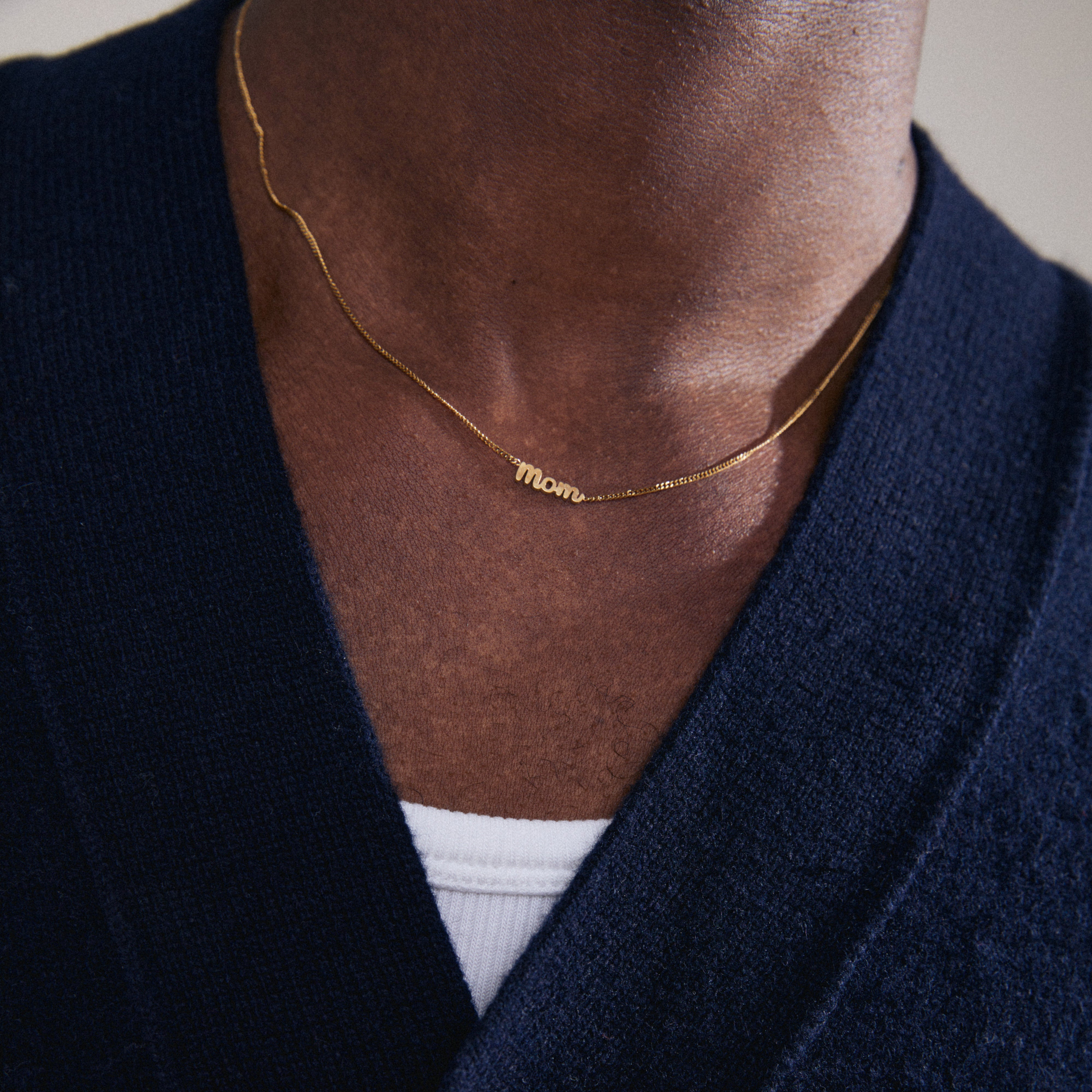 Gold-plated 'MOM' necklace with a cursive pendant, worn by a person. A versatile, eco-friendly piece perfect for daily wear and gifting.