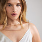 HOPE necklace gold-plated on a woman wearing a white dress, showcasing its delicate cursive pendant. Perfect for daily wear and gift-giving.