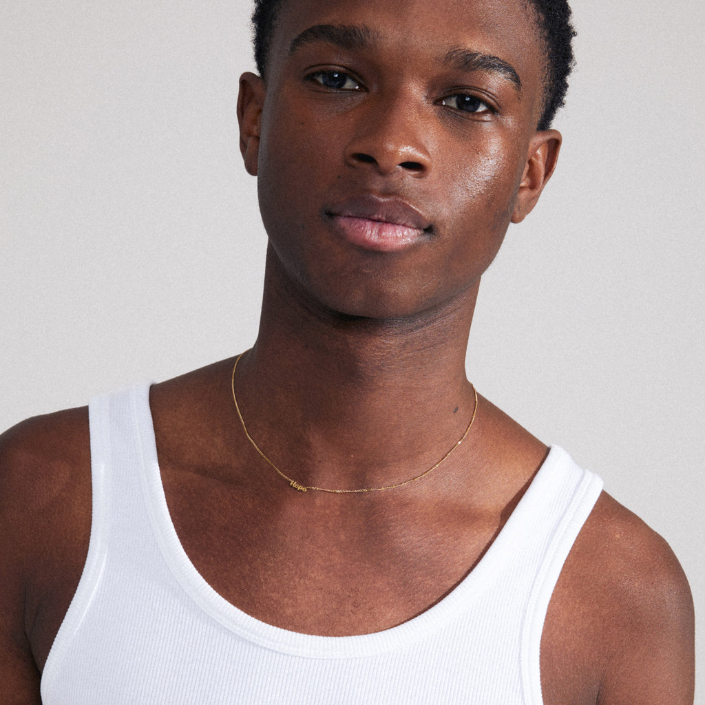 Gold-plated HOPE necklace shown on a man wearing a white tank top; features a cursive script pendant. Ideal for personal styling or gifting.